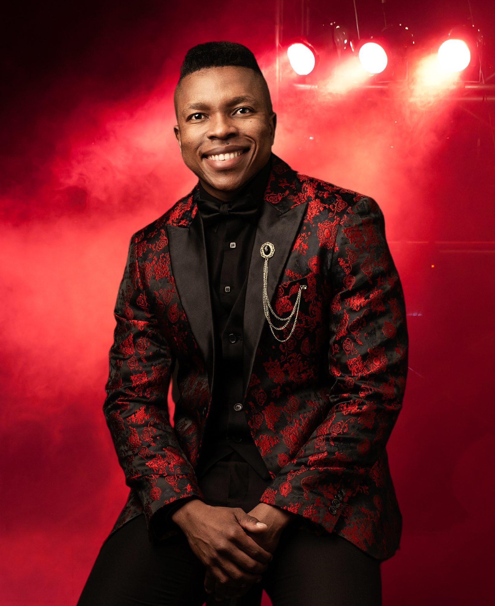 Thuba Myeki on stage in a red brocade jacket